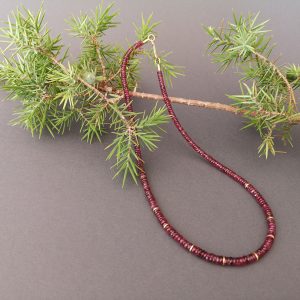 Eine Kette die aus vielen kleinen Turmalin-Steinchen besteht. Der Verschluss ist aus Gold.