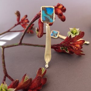 Ohrstecker mit Opal an dem ein goldener Stift hängt der mit einer Perle abschließt.